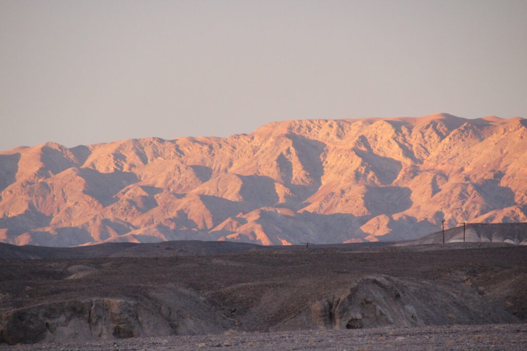 Death Valley mountains turning orange and gold in the last of the evening light above grey rock