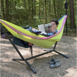 Reading a book while sitting in yellow hammock in hammock stand.
