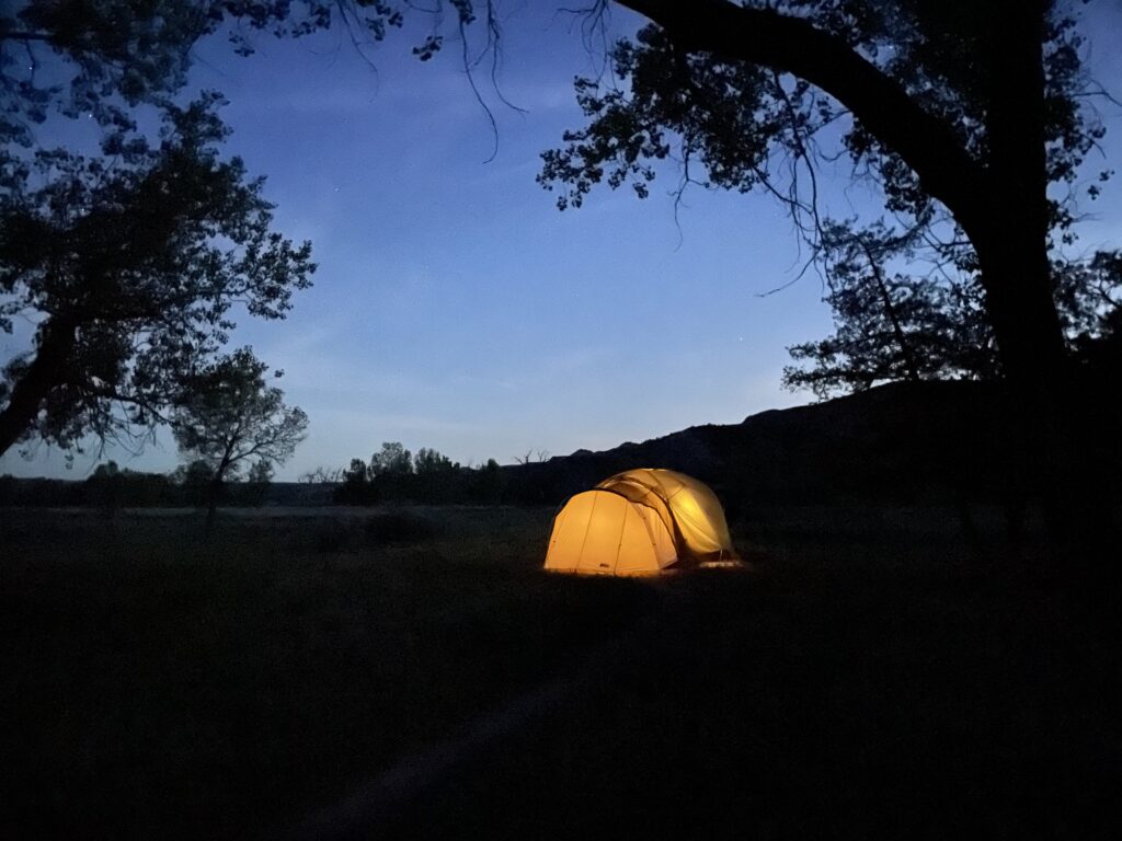trnp-tent-at-dusk A lit tent glowing under a cottonwood tree at dusk, Cottonwood Campground, Theodore Roosevelt National Park